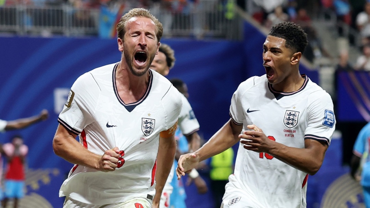 Harry Kane comemora em campo com a seleção da Inglaterra durante a Copa do Mundo, em imagem de jogo com atletas ao fundo e expressão de vitória, destacando o craque britânico