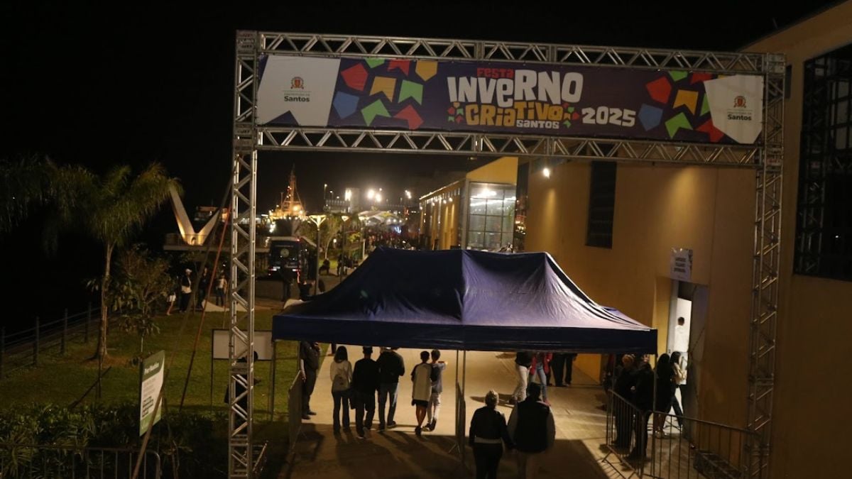 Entrada do Parque Valongo em noite de evento com estrutura metálica e telão do Inverno Criativo, tendas montadas e público circulando, no contexto da Festa Inverno Criativo 2026.