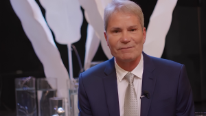 Pastor Márcio Poncio em entrevista, usando terno azul e gravata clara, em cenário de estúdio, em imagem associada à notícia de Pastor Márcio Poncio preso pela PF na Operação Unha e Carne.