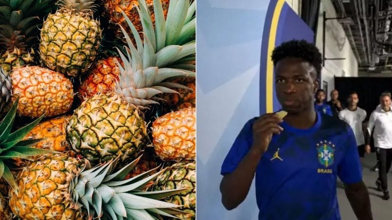 Vini Jr. aparece em foto segurando um pedaço de abacaxi, enquanto ao lado há abacaxis inteiros e com folhas, em uma imagem que remete ao hábito de comer abacaxi antes dos jogos.