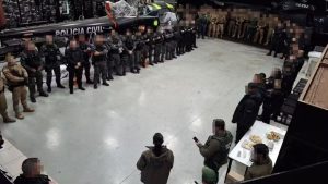 Megaoperação da Operação Coluna Sul em Mogi Guaçu: agentes da Polícia Civil formam fila em um pátio interno, com viaturas e equipe de segurança ao redor, durante ação de combate ao crime.