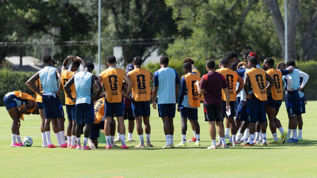 Grupo da seleção de Cabo Verde reunido em treino no campo de futebol, jogadores com uniformes em preparação para enfrentar a Argentina, orientações durante o aquecimento.
