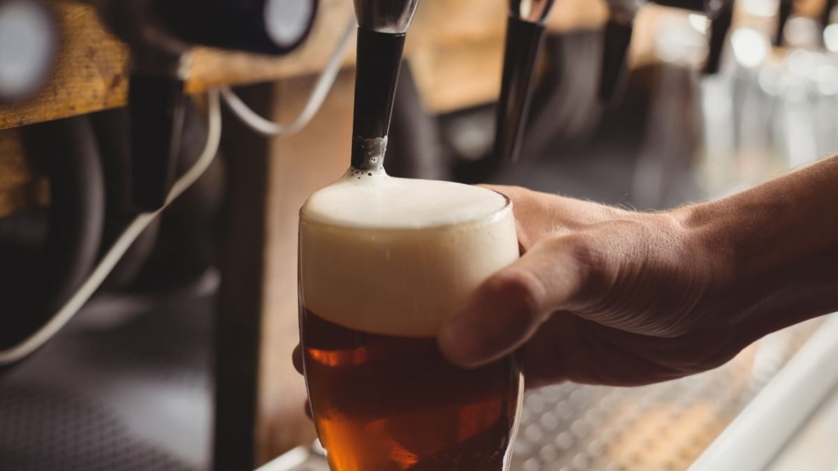 Rota da Cerveja de São Paulo em Indaiatuba: mão brindando com um copo de cerveja artesanal com espuma, em clima de visita às cervejarias