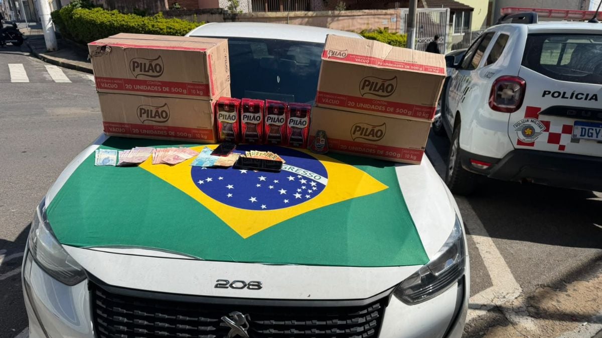 Café furtado em Atibaia: caixas de café da marca Pilão e pacotes com café apreendidos em abordagem da Polícia Militar, ao lado de viatura e bandeira brasileira no capô do carro