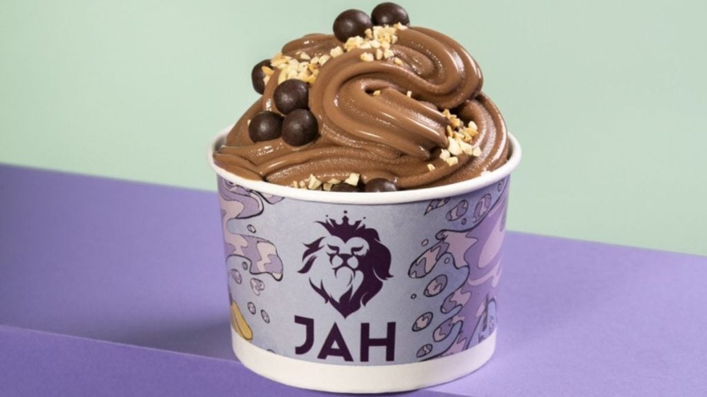 Pote de sorvete com creme de chocolate decorado com gotas de chocolate, raspas e granulado, em fundo claro, ideal para o Dia do Chocolate.