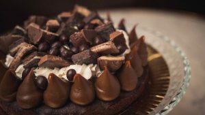 Dia do Chocolate: tigela com bombons e pedaços de chocolate ao leite e meio amargo, com chocolate quente cremoso ao fundo, clima de inverno e aconchego