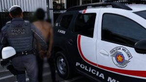Polícia Militar com viatura na frente de um homem algemado, em registro que ilustra tentativa de latrocínio em Atibaia após roubo e tentativa de homicídio.