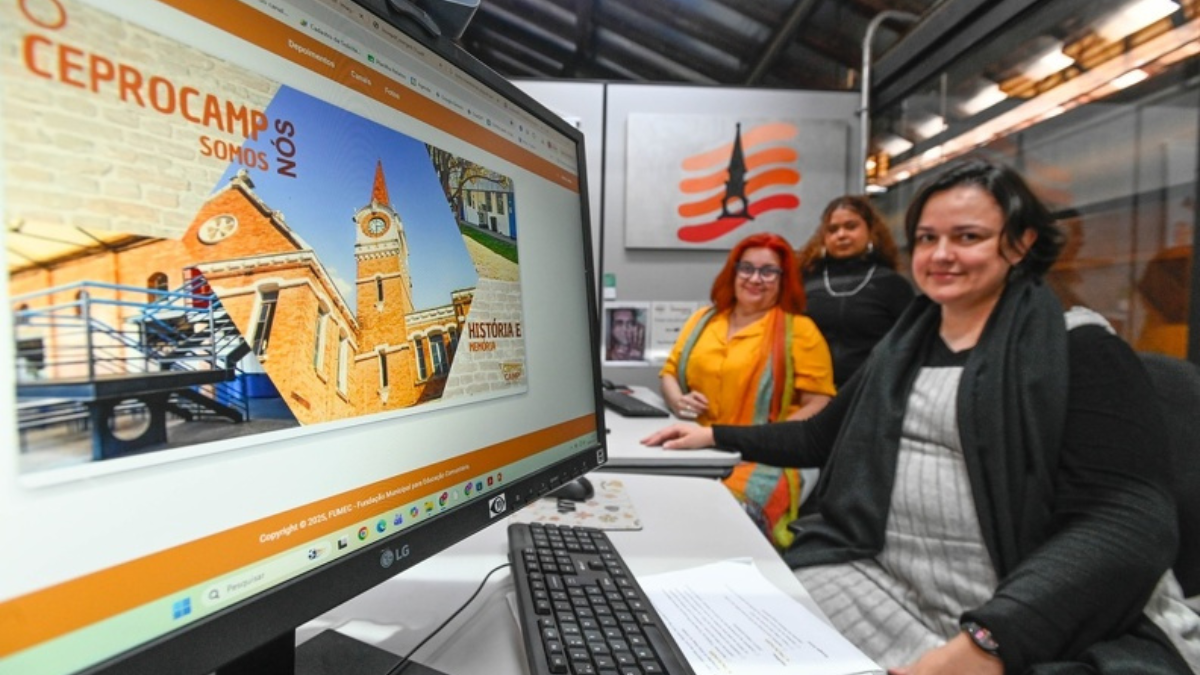 Equipe em ambiente de escritório com monitores exibindo material institucional e uma pessoa ao lado de um computador, representando divulgação de cursos gratuitos em Campinas para qualificação profissional.