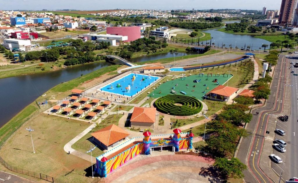 Vista aérea do Parque da Criança em Indaiatuba, com piscinas e brinquedos ao lado do rio, cenário ideal para o feriado de 9 de julho.