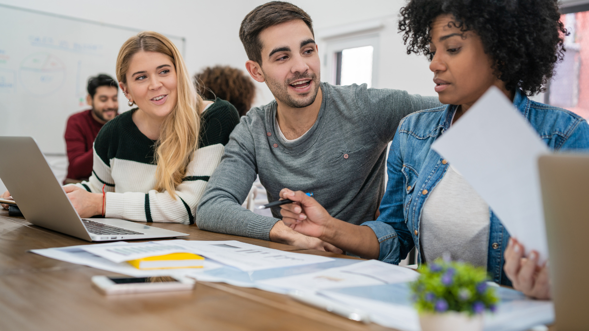 Estudantes em reunião na mesa com laptops e documentos, colaborando em equipe, representando inscrições para estágio TRE-SP com prazo até domingo (12).