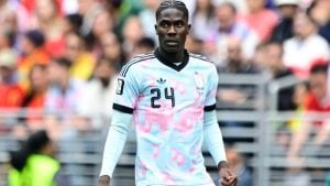 Onana em campo, vestindo a camisa da seleção, durante partida disputada em um estádio com torcida ao fundo. Amadou Onana aparece em foco no momento do jogo.
