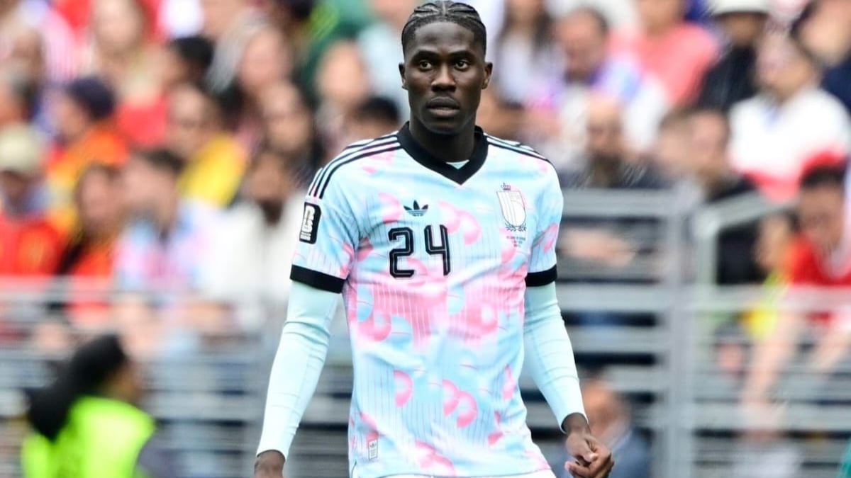 Onana em campo, vestindo a camisa da seleção, durante partida disputada em um estádio com torcida ao fundo. Amadou Onana aparece em foco no momento do jogo.