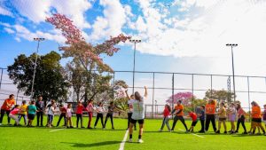 Crianças e adolescentes brincam e praticam atividades ao ar livre em uma área de grama no Sesi, em imagem de divulgação do Super Férias Sesi com inscrições nas cidades de Santos, Cubatão e Registro.