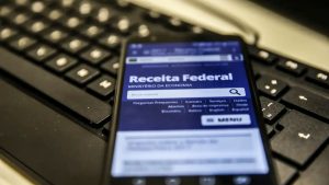 consultar restituição ir: Celular com site da Receita Federal aberto, mostrando informações para consultar a situação da restituição do Imposto de Renda. Ainda não recebeu o IR? Veja como consultar a restituição ir.