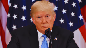 Donald Trump em pronunciamento à imprensa nos Estados Unidos, diante de bandeiras americanas, em contexto de declarações sobre o Acordo de paz EUA Irã após novos ataques no Golfo.
