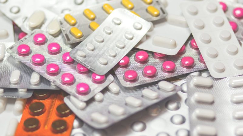 Cartela com comprimidos e medicamentos variados, com caixas de blísteres sobrepostas, reforçando a ideia de preços de medicamentos que podem variar muito entre farmácias de SP.
