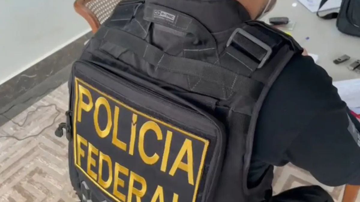 Policial federal com colete preto escrito “POLICIA FEDERAL”, em cenário de operação contra facções, cumprindo mandados em Campinas, Santos e outros estados.