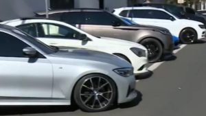 Fluente de carros de luxo apreendidos em Limeira, com veículos brancos estacionados na rua, usados na operação ligada à fraude de R$ 9 milhões.