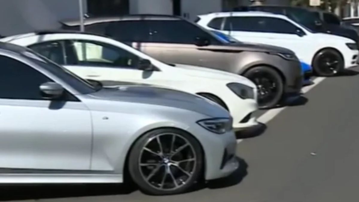 Fluente de carros de luxo apreendidos em Limeira, com veículos brancos estacionados na rua, usados na operação ligada à fraude de R$ 9 milhões.