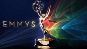 Troféu do Emmy com efeitos de luz e fundo azul escuro com a inscrição "EMMYS", imagem usada na chamada sobre indicados ao Emmy 2026 nas principais categorias da premiação.