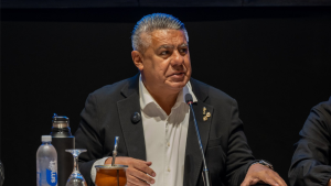 FBI investiga AFA: imagem mostra um homem em traje escuro discursando em um evento, ao lado de microfone e copo, em contexto de apuração de operações financeiras da Federação Argentina nos Estados Unidos.