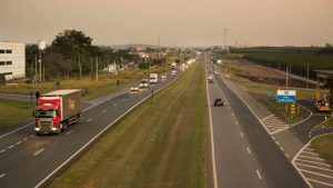 Rodovias com tráfego intenso em dia de feriado, com caminhões e carros seguindo pela via ao entardecer. Cena que ilustra o fluxo de veículos no feriado de 9 de julho.