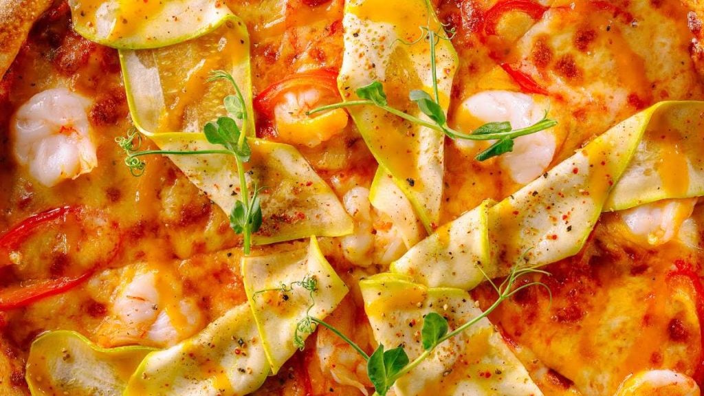 Dia da pizza com diversas fatias de pizza de queijo e vegetais, com manjericão e ervas frescas sobre a massa, destacando opções vegetarianas e veganas.
