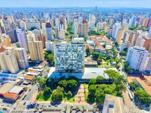 Vista aÃ©rea de Campinas com prÃ©dios e ruas, ilustrando a queda nos roubos de veÃ­culos na regiÃ£o de Campinas, que recuam e atingem menor marca histÃ³rica.