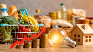Inflação medida pelo IPCA junho 2026 em contexto de alimentos mais baratos e energia: carrinho de compras com vegetais e frutas, moedas com seta de alta e lâmpada ao lado de casas em miniatura.