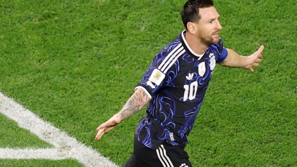 Argentina na semifinal contra a Inglaterra: jogador usando camisa azul e preta com o número 10, celebrando em campo verde com chuteiras e marcas de gramado, gesto de comemoração.