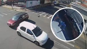 Cena de trânsito em Itapira vista de câmera de segurança, com veículos na via e um recorte ampliado mostrando pessoas próximas a uma caminhonete durante briga após empurrão.