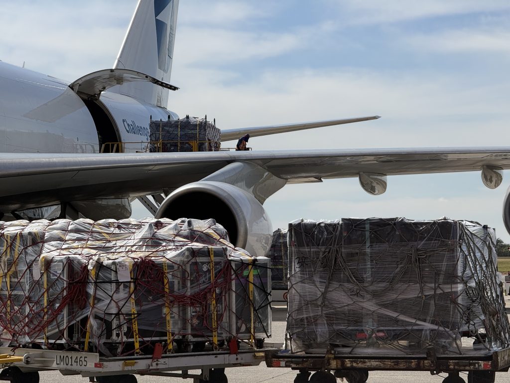 Harry Styles Viracopos: carga de equipamentos embrulhados em fardos e caixas sendo transportada a bordo de um avião em área de pátio aeroportuário, com a fuselagem aberta para operação logística dos shows em SP.
