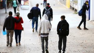 Pessoas caminhando na rua em dia frio, com roupas pesadas e capuzes, em alerta da Defesa Civil para frio intenso em SP entre hoje e quinta-feira.