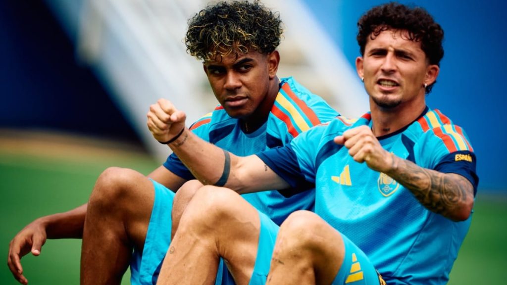 Espanha na Copa do Mundo: dois jogadores da seleção espanhola em campo comemoram com expressões de vitória, usando uniformes azuis e listras, em imagem esportiva que remete ao título.