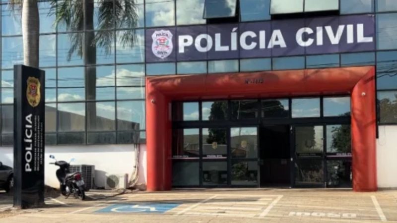 Entrada da Polícia Civil em Americana, com placa “Polícia Civil” e fachada com portão vermelho, usada em reportagem sobre mãe presa em Americana