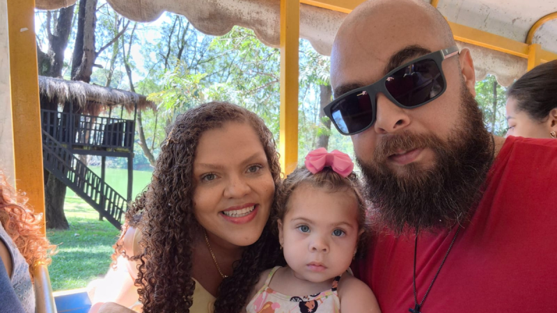 Família reunida em um ambiente externo, com casal e uma criança no colo, transmitindo preocupação e esperança em busca de um remédio para doença rara, em Indaiatuba. Contexto envolve tri-heptanoína para VLCAD.