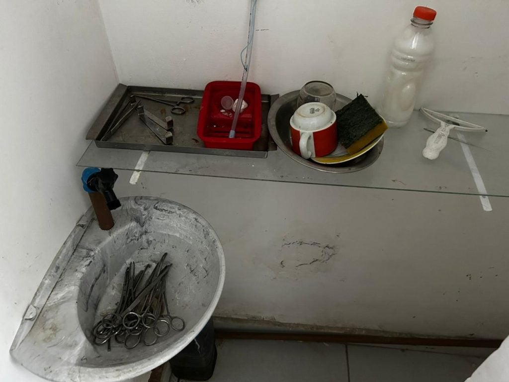 Interior de sala de clínica veterinária interditada em Mongaguá, com instrumentos e materiais em bancadas, sem identificação de atendimento ao público, indicando irregularidades e fechamento