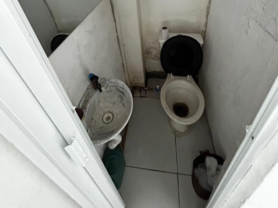 Ambiente sanitário interno com vaso sanitário e um segundo recipiente sanitário em banheiro fechado, com sinais de irregularidades e descuido, representando uma clínica veterinária fechada em Mongaguá.