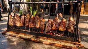 ExpoGaúcha em Santos: espetinhos de carne assando em uma churrasqueira com brasa e grelha, ilustrando a culinária do Sul em evento ao ar livre.