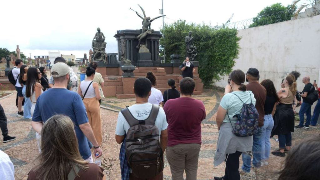 Participantes em uma visita guiada no Cemitério da Saudade, caminhando em grupo entre túmulos e observando estátuas e monumentos em uma escadaria, com duração aproximada de 2h30. (Divulgação/Toninho Oliveira)