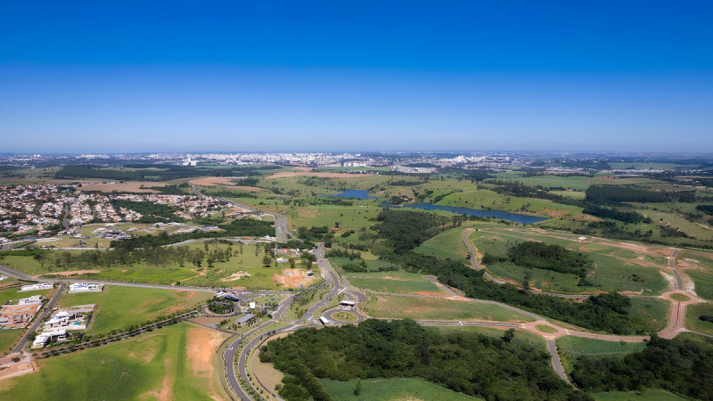 Vista aérea de uma região com terrenos e obras de loteamentos em Campinas, destacando estradas internas e áreas verdes ao redor, relevante para o mercado de loteamentos em SP no 1º trimestre.