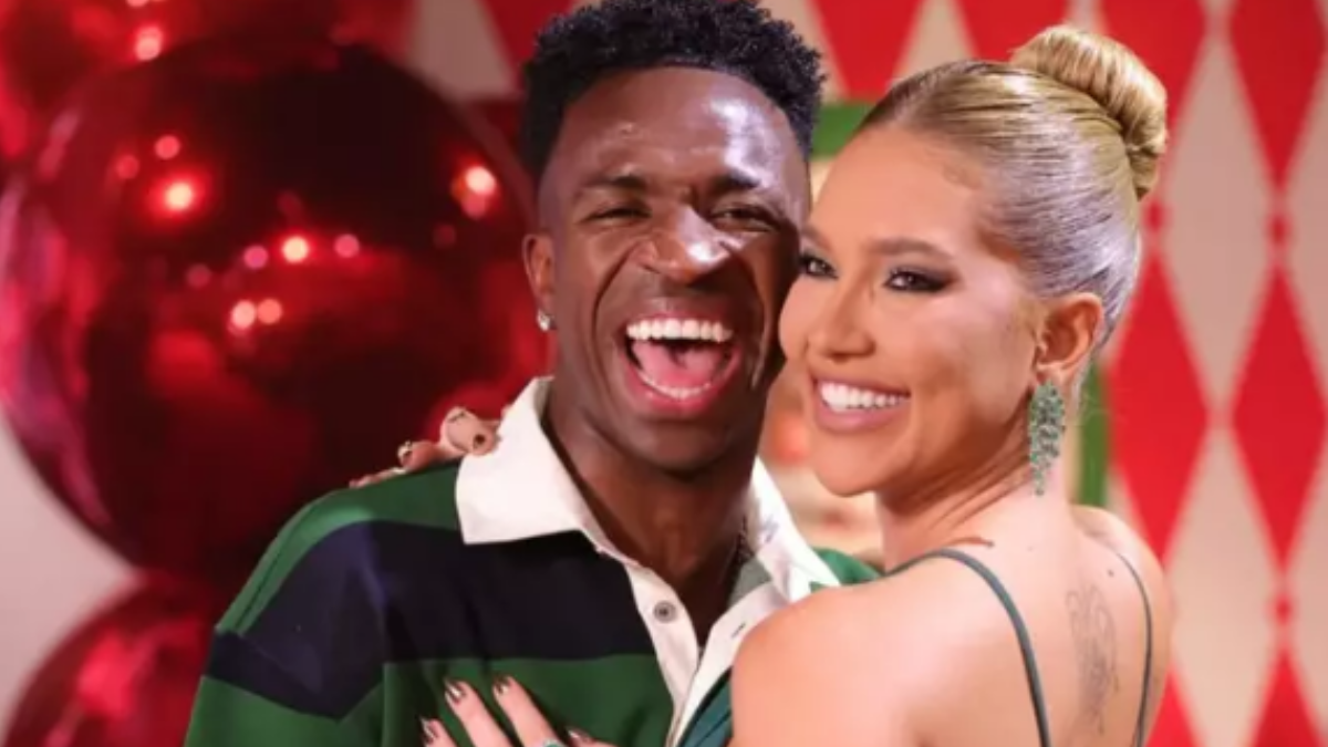 Virginia e Vini Jr aparecem sorridentes ao lado em foto promocional, em clima de comemoração, com decoração vermelha e verde ao fundo.