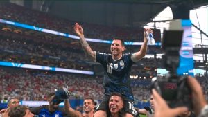 Lionel Messi levanta as mãos em comemoração no estádio, com troféu na cabeça e camisa da Argentina, após vitória histórica e como favorito à Messi Chuteira de Ouro 2026.