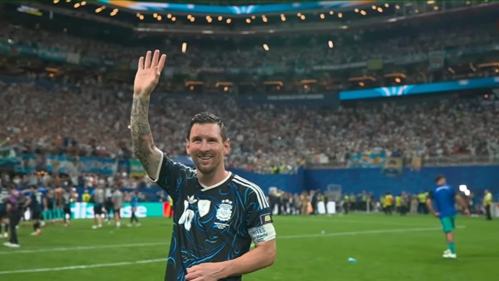 Messi celebra no estádio após partida histórica, levantando a mão para a torcida, em imagem que destaca Messi Chuteira de Ouro 2026 como favorito após Copa do Mundo marcante.