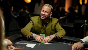 Neymar pôquer: jogador em mesa de poker em ambiente de cassino, com fichas coloridas sobre a mesa e cartas em destaque, sorrindo durante a partida.