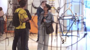 Turistas em um museu de Campinas durante visita gratuita, observando uma exposição com objetos e peças no interior do espaço cultural.