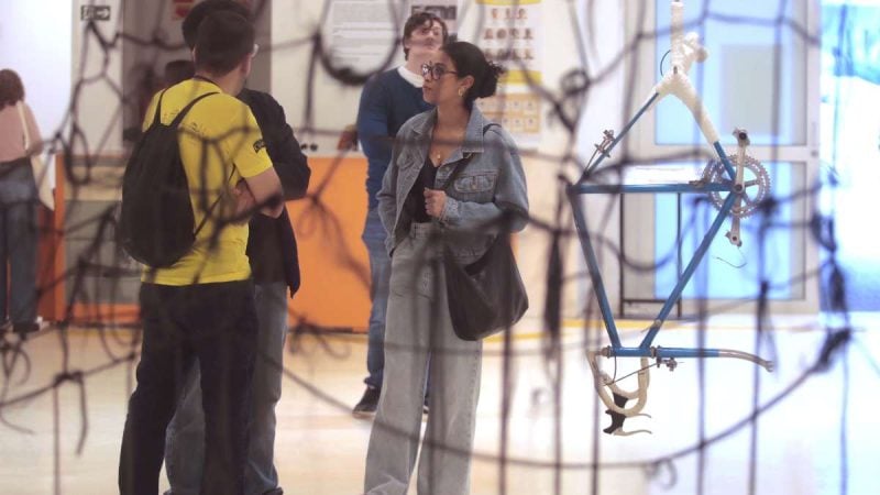 Turistas em um museu de Campinas durante visita gratuita, observando uma exposição com objetos e peças no interior do espaço cultural.