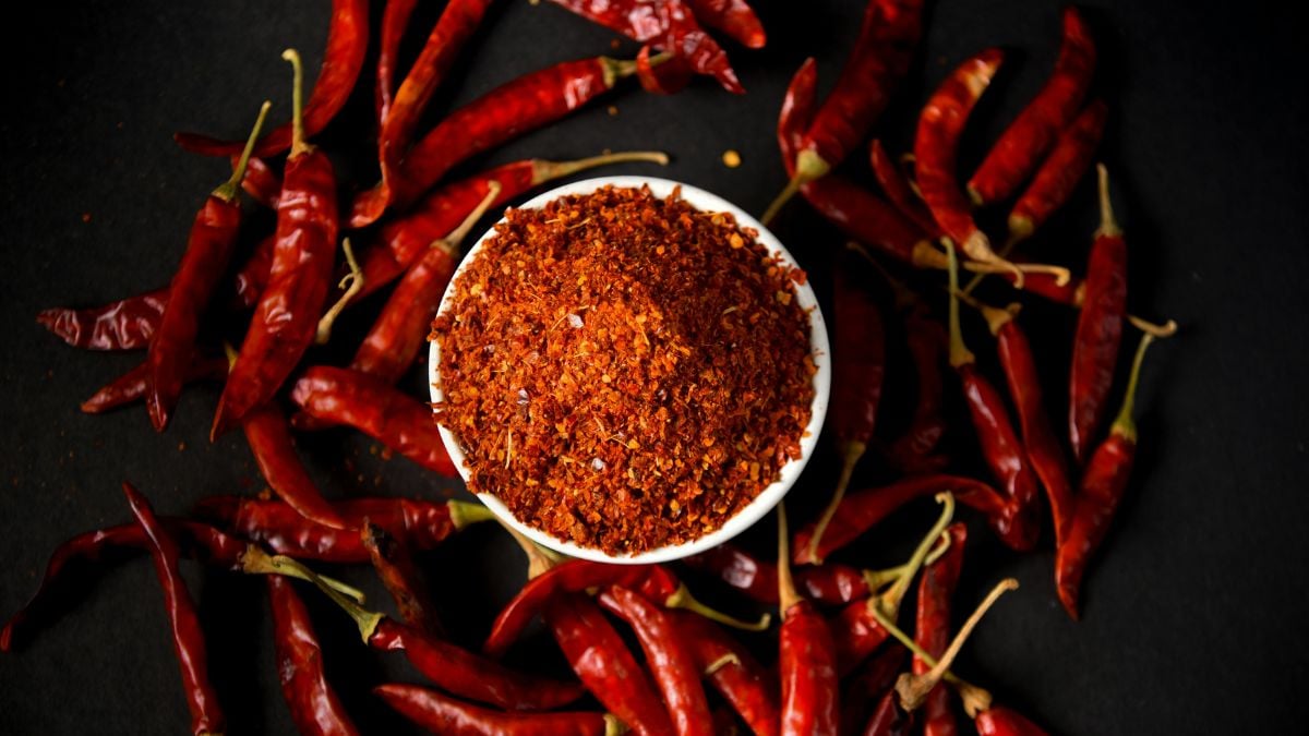 Pimentas vermelhas ao redor de um recipiente com especiaria em pó, destacando tipos de pimenta e diferentes níveis de ardência para ir do suave ao explosivo.