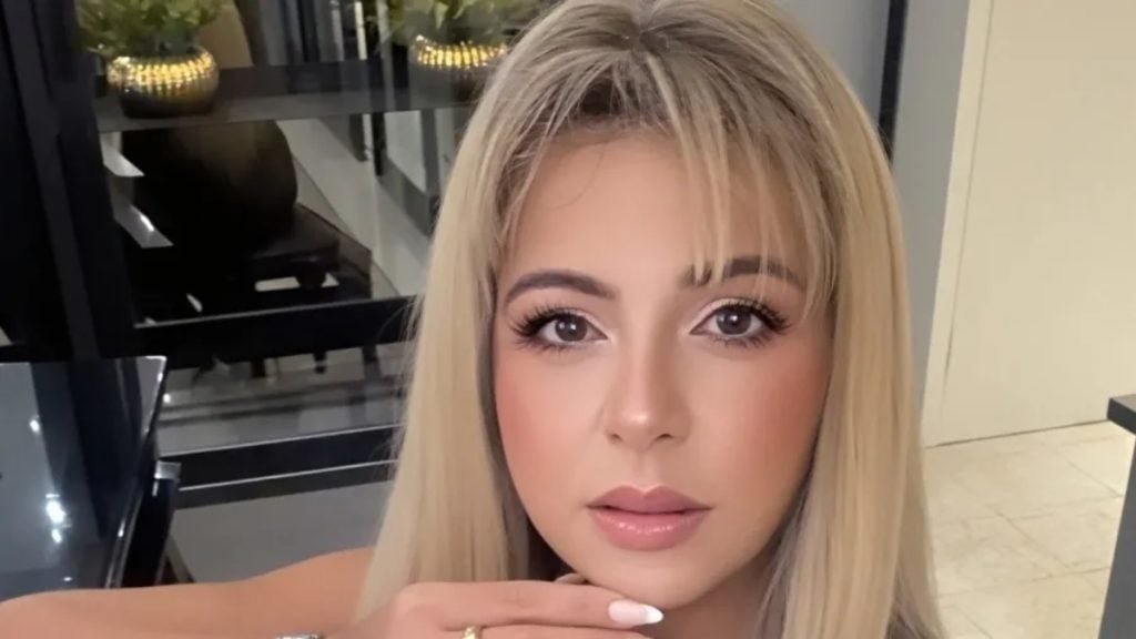 Vó Bahiana em close, com cabelo loiro e maquiagem marcante, em ambiente interno, fazendo nova previsão e revelando palpite sobre a final da Copa do Mundo.