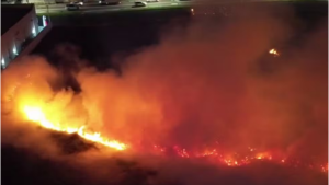 Incêndio em terreno em Hortolândia: imagem noturna com chamas intensas e fumaça densa em área particular, com foco no fogo avançando pelo mato.